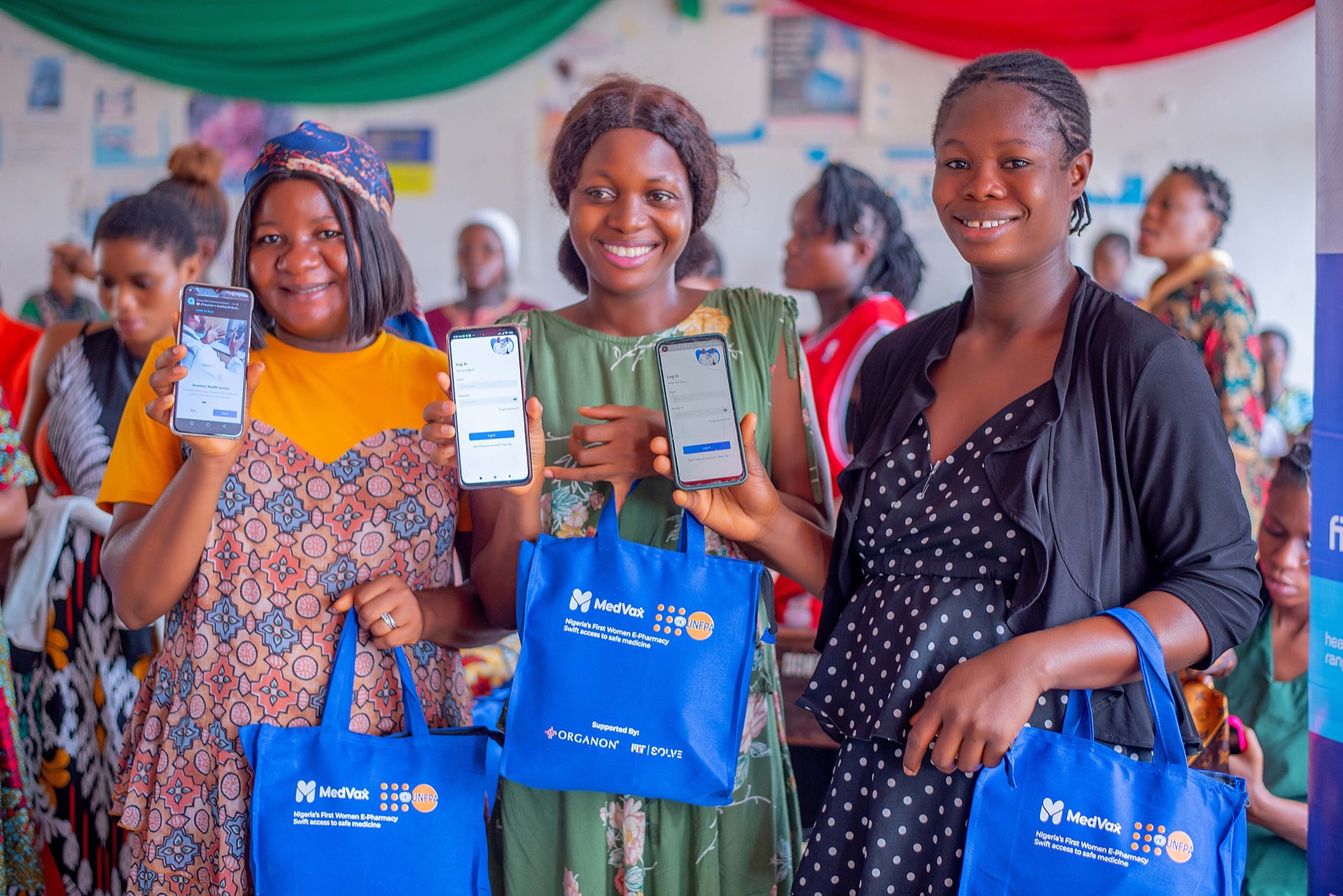 Founders holding up a maternal-health app and e-pharmacy tote bags at a Hanga SRH event